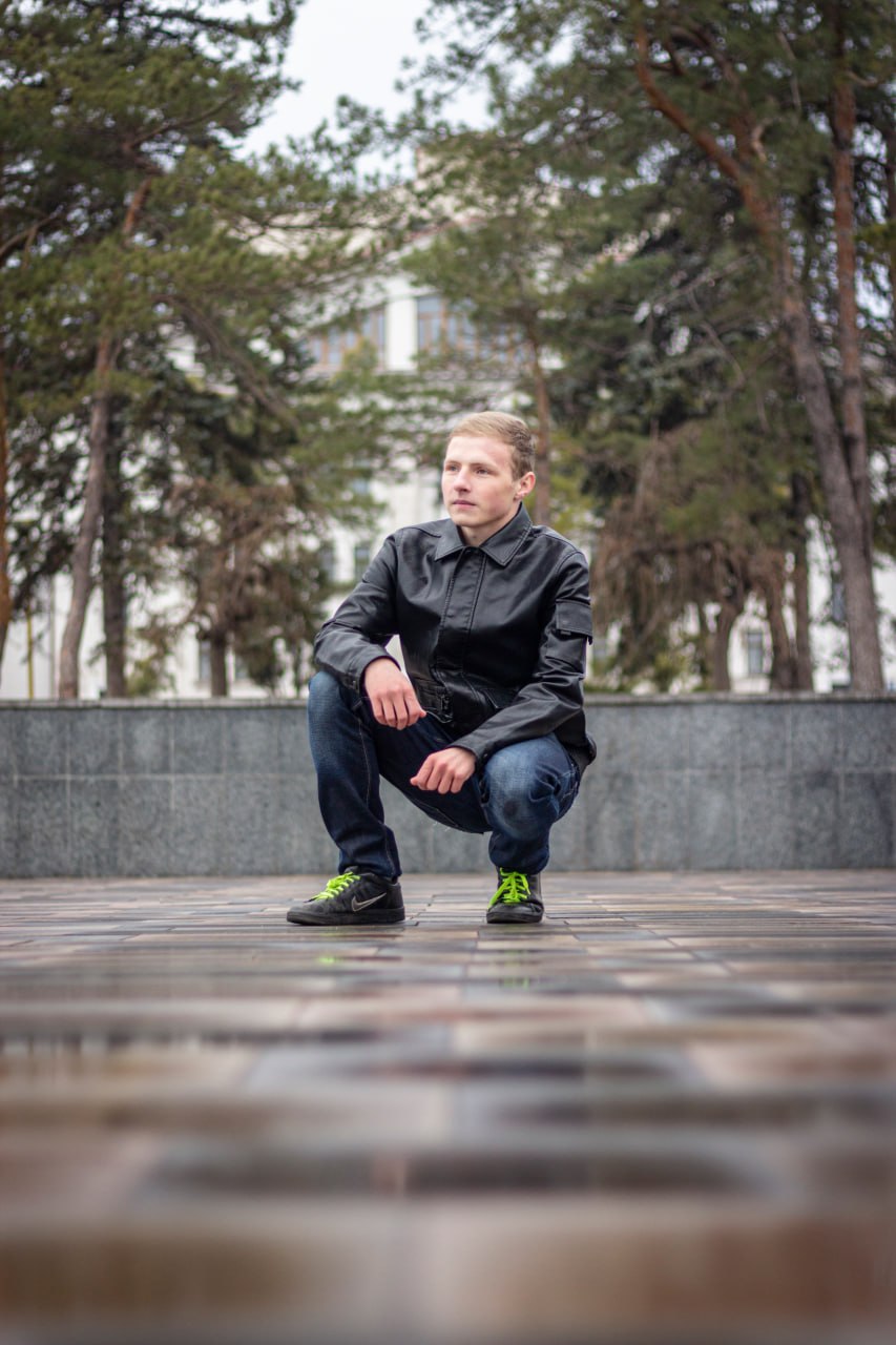 Валентин на корточках у здания